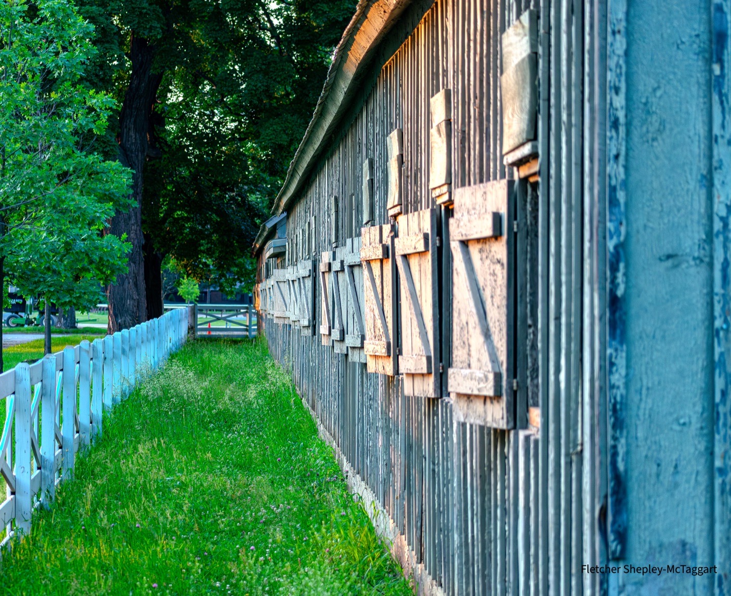 The side of a weathered stable is shaped by cool and warm light.