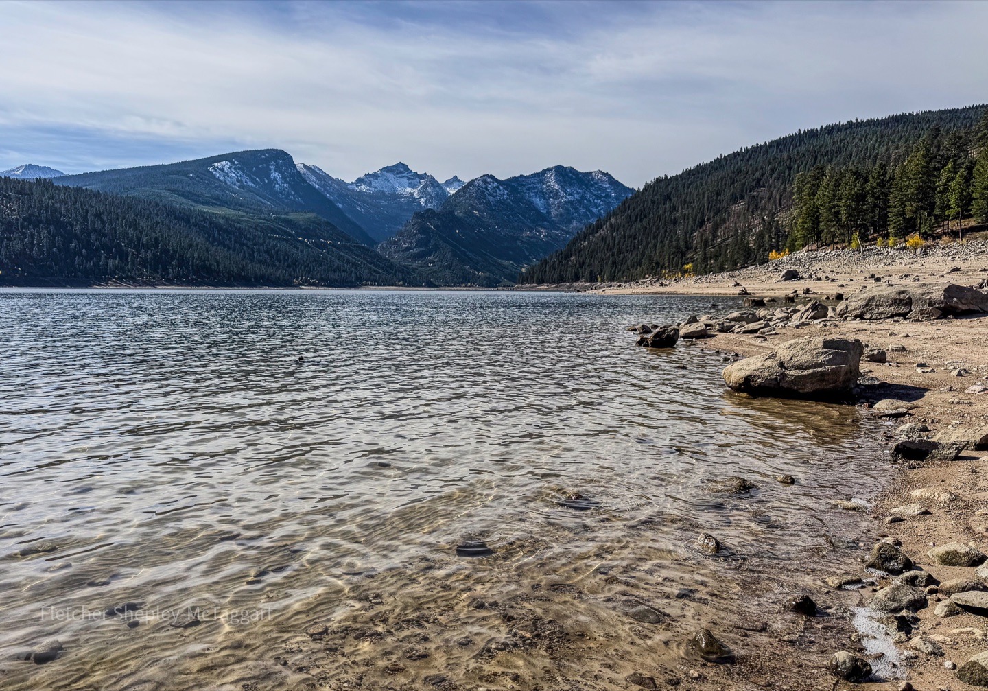 A clear mountain lake reflects light below snow-covered peaks.